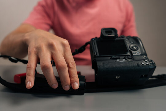 Detail cropped shot of videographer holding camera with attached battery grip, integrating external power supply for extended shooting sessions and enhanced vertical handling, close-up, cropped shot.