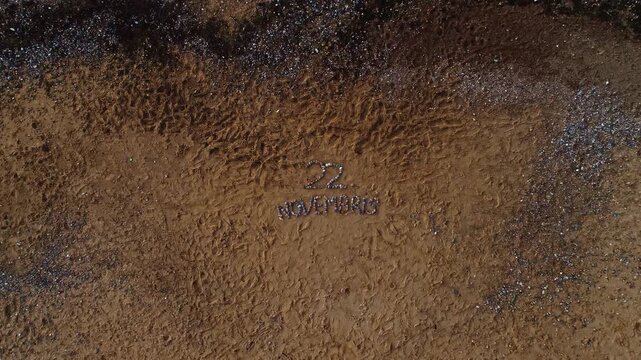 Aerial view of stones arranged on a sandy beach to spell out 22 Novembris in Latvia.
