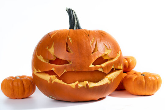 A close-up of a hollowed-out pumpkin with a face carved into it. The background is white.