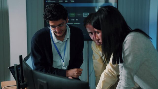Software team solving problem, colleagues looking at computer screen together in tech office