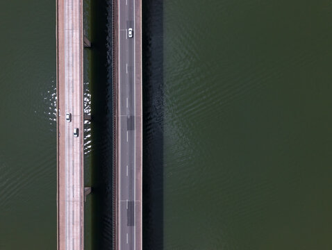 Aerial view of two parallel bridges crossing over dark water with cars driving on the asphalt lanes in Brazil.