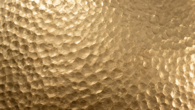 Hammered gold metal texture, champagne gold hammered brass sheet with soft dimpled facets and gentle sheen, luxury golden background