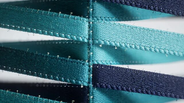 Shifting camera focus revealing vertical stitched seam in studio macro, with teal navy straps