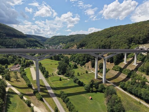 Aerial view of the Filstalbrucke, a prominent high-speed railway bridge spanning a lush green valley with a road below in Muhlhausen im Tale, Baden-Wurttemberg, Germany.