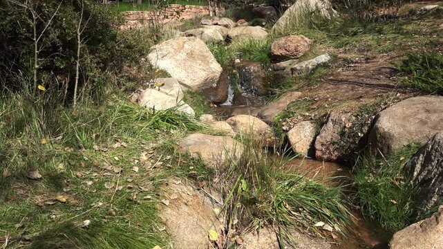 Small Colorado Stream Trickling out of Mountains 4K Loop features a small stream of water running down a hill over rocks in Colorado in a loop.