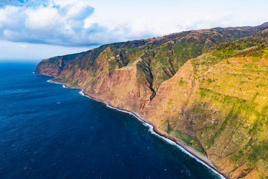 Madeira sea cliffs divided by deep coastal valleys, Portugal. Broad aerial landscape of steep slopes descending to Atlantic Ocean