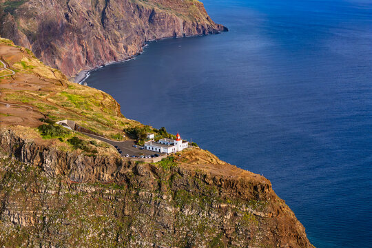 Western Madeira coastline with Ponta do Pargo lighthouse and high sea cliffs, Portugal. Coastal sightseeing destination overlooking Atlantic Ocean.