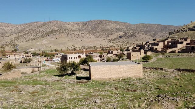 Killit village, Dereici, near Savur, Mardin, Turkey: Syriac stone houses, many in ruins, spread over a green hillside below dry hills