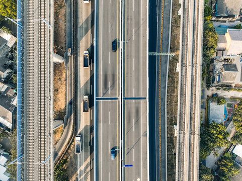Aerial view of a multi-lane highway with vehicles and parallel railway tracks running through an urban area in Bekasi Barat, West Java, Indonesia.
