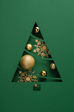 Green paper cut tree with gold ornaments and snowflake decorations &mdash; creative vision for Merry Christmas and Happy New Year on vertical luxurious green modern backdrop