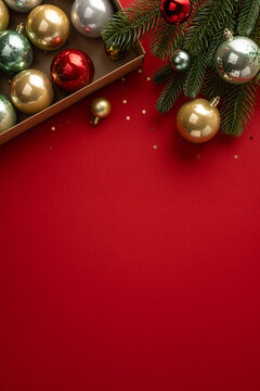 Merry Christmas decorations with baubles and fir branches for a happy New Year greeting on vertical bright red template for advert
