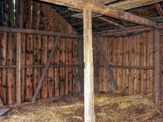 Empty interior of rustic wooden barn with straw on ground before hay storage © Ivan Koliadzhyn