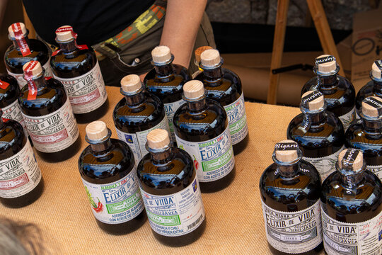 DENIA, SPAIN - SEPTEMBER 26, 2026: Glass bottles of Spanish Elixir de Vida artisan flavored extra virgin olive oil displayed for sale at an outdoor market stall.