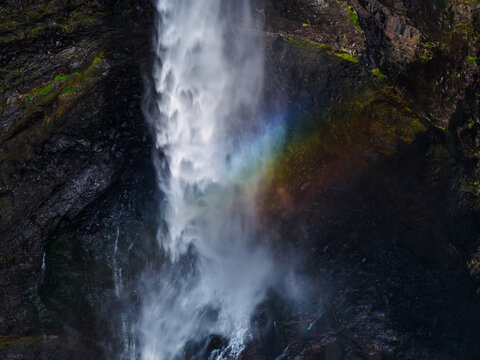Aerial view of Kalu Water Fall cascading down dark rocky cliffs with a visible rainbow in the mist in Khireshwar, Maharashtra, India.
