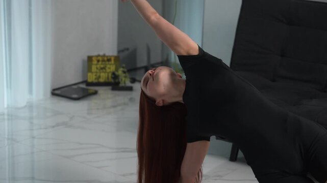 Athletic woman performing a side plank with a backbend yoga pose on a mat for flexibility and strength training at home