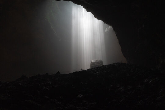 Aerial view of Jomblang Cave with dramatic light beams illuminating the dark rocky interior in Kecamatan Semanu, Daerah Istimewa Yogya, Indonesia.