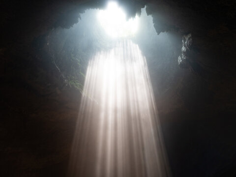 Aerial view of Jomblang Cave with dramatic light beams streaming through the sinkhole opening into the dark cavern, Kecamatan Semanu, Daerah Istimewa Yogya, Indonesia.