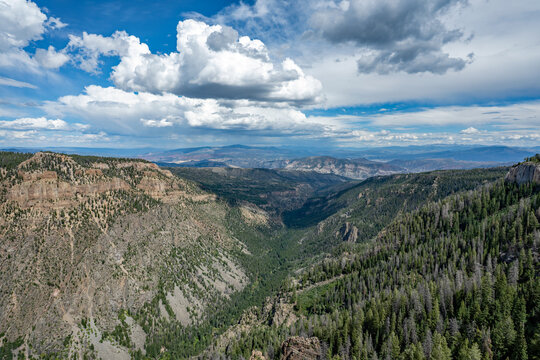 Elevated view of Deep Creek and surrounding mountains from Deep Creek Overlook in Colorado Flat Tops Wilderness under sunny summer cloudscape.