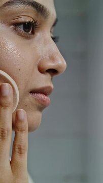 Vertical video: Using woman pressing wiping lifting round pad on cheek at sink cleansing damp skin
