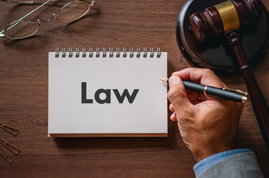 Law written on spiral notebook with judge's gavel nearby &mdash; ideal eye-catcher for legal profession articles and law firm websites