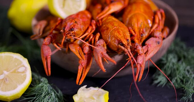 Red boiled crayfish next to a yellow slice of lemon, fresh boiled crayfish with a textured orange shell are ready to eat