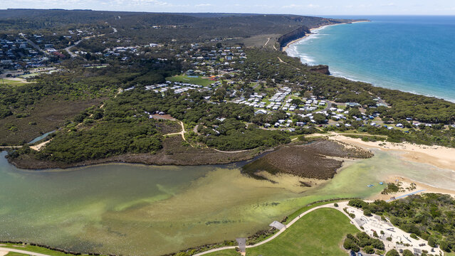 Aerial drone view over the coastal regional town of Anglesea, Victoria, Australia, with the Anglesea River inlet and sandbars of the estuary, sandy river mouth, coastal cliffs.
