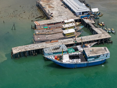 Aerial view of fishing boats moored at a concrete pier with calm turquoise water in Kotabaru Regency, South Kalimantan, Indonesia.