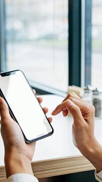 Vertical video: Tapping hands with pale cuff browsing phone after hover at cafe window