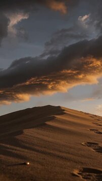 Vertical video: Tilting camera showing dune crest in desert to reveal footprints and sky texture