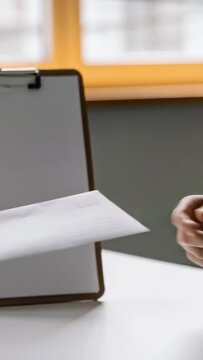 Vertical video: Extending left hand passing envelope at office for handoff to right hand, clipboard
