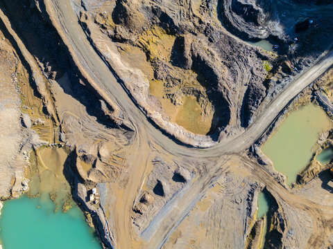 Aerial view of an open-pit quarry with deep excavation pits, dirt roads, and pools of turquoise and murky water in Rathmore, County Kildare, Ireland.