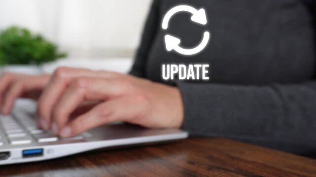 Person types on laptop with 'UPDATE' text appearing. Symbolizing software update. Background shows modern office desk and plant. Ideal for tech, IT, or software update content