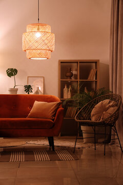 Cozy home interior with warm lighting, modern living room design with orange velvet sofa and rattan furniture for comfortable lifestyle and relaxation