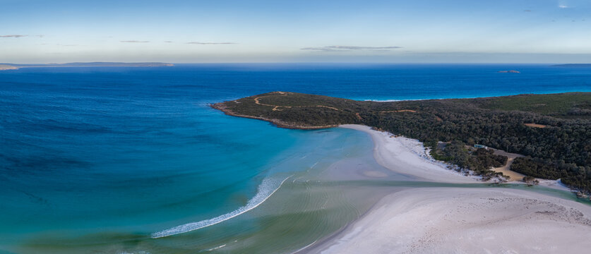 Aerial view of the white sand beach and turquoise waters of Bremer Bay, surrounded by dense coastal vegetation and rocky headlands in Bremer Bay, Western Australia, Australia.