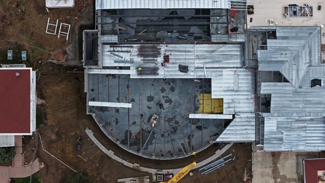 Aerial view of a construction site featuring a partially completed building with metal roofing, steel beams, and workers on the ground, Estes Park, Colorado, United States.
