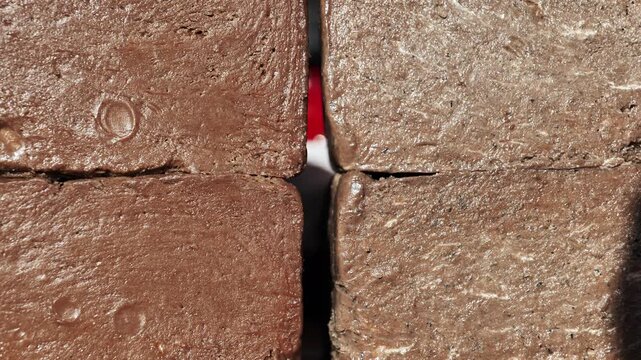 Four blocks of homemade chocolate fudge creating a textured, sweet, brown background