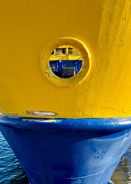 Porthole in a Yellow Ferry Bow Above a Blue Hull
