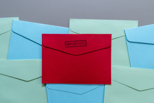 Red envelope stamped IMPORTANT on top of blue and green envelopes. Priority mail, urgent communication, critical notices, alerts, important correspondence concept