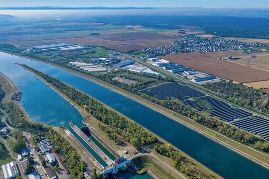 Aerial view of the Grand Canal d'Alsace lock system, industrial facilities, solar panel fields, and agricultural land, Hombourg, Grand Est, France.