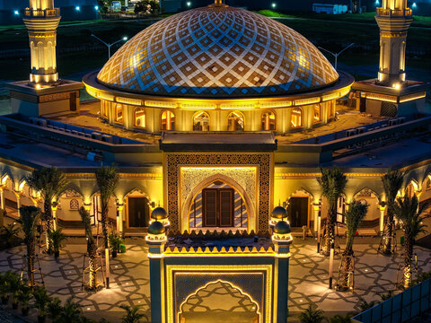 Aerial view of Masjid Al-Ikhlas PIK illuminated at night, featuring its intricate dome, minarets, and landscaped courtyard in Jakarta Utara, Daerah Khusus Ibukota, Indonesia.