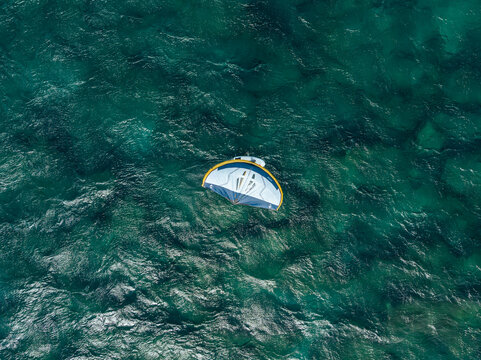 Aerial view of a wing foil gliding over the turquoise waters of the Pacific Ocean near Maui, Hawaii, United States.