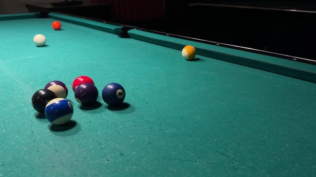 Pool player makes an unsuccessful attempt to pocket an orange ball with the white cue ball on a billiard table, close view of missed shot during casual indoor game, horizontal video