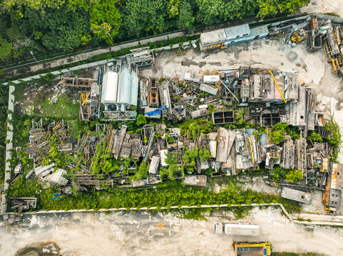 Aerial view of an industrial site featuring heavy machinery, storage tanks, and metal structures surrounded by lush green vegetation in Klapanunggal, West Java, Indonesia.