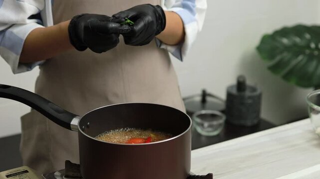 Tearing kaffir lime leaves into a boiling Thai soup pot
