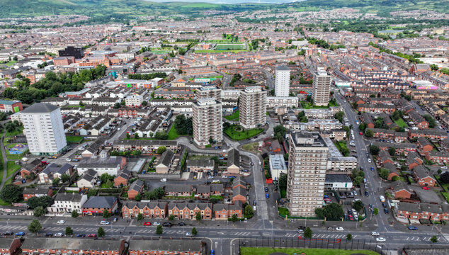 Aerial view of New Lodge featuring high-rise residential tower blocks, dense rows of terraced houses, and urban streets in Belfast, Northern Ireland, United Kingdom.