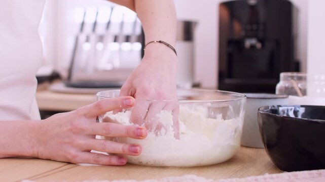 Baker occupation. Homemade cuisine. Woman chef hand kneading cottage cheese with white flour in glass bowl preparing healthy dairy dish.
