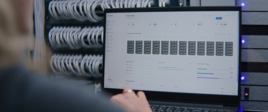 Female IT Engineer Reviewing Server Status and Infrastructure Analytics on Laptop. Cloud Computing Management, Hardware Performance Assessment, Network Reliability, and Enterprise IT Administration.