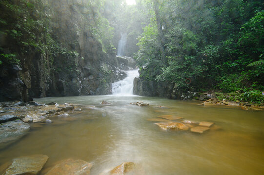 Serene Forest River with Waterfall and Natural Rocky Shoreline