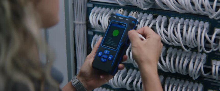 Female System Administrator Performs Ethernet Port Testing With Cable Tester, Verifying Network Hardware Connections and Supporting Reliable Data Transmission Within Modern Server Environment.