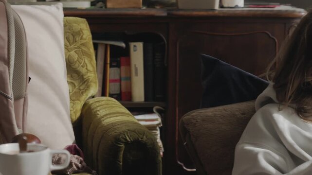Young woman wrapped in blankets at home uses her mobile phone to stay in contact with friends, showing social connection despite being unwell.